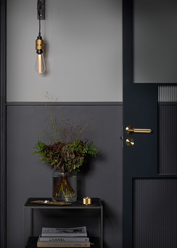 Buster + Punch Linear Door Handle - Sprung with side table holding a vase with flowers and a hanging light