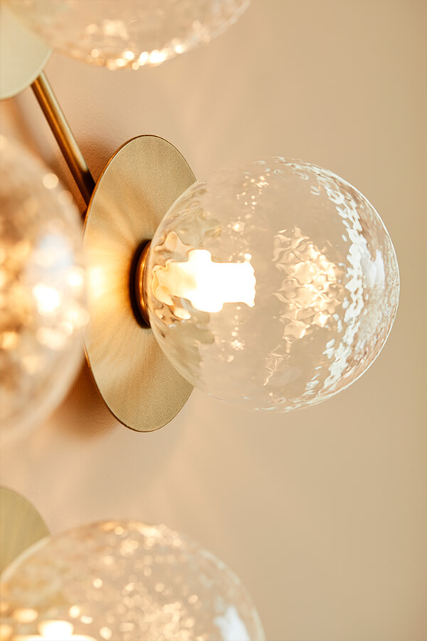 A close up of the gold and glass Liile 12 wall light from Nuura