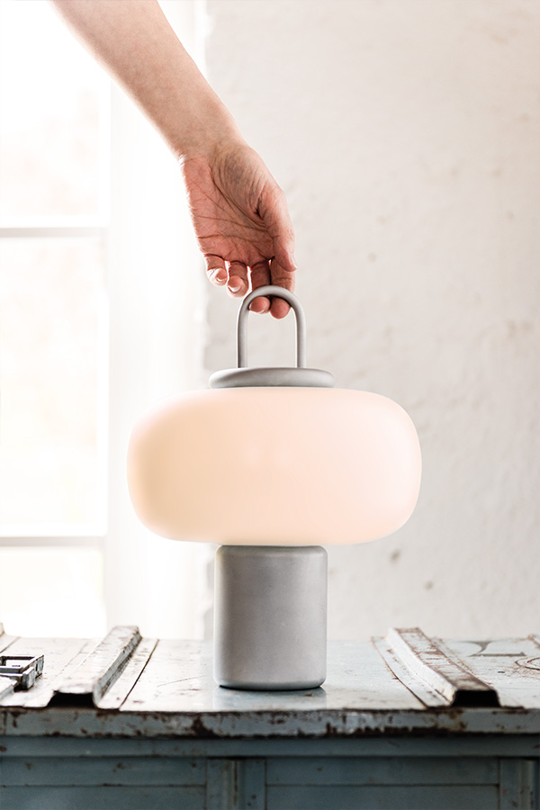 Someone picking up the Nox table lamp using its handle