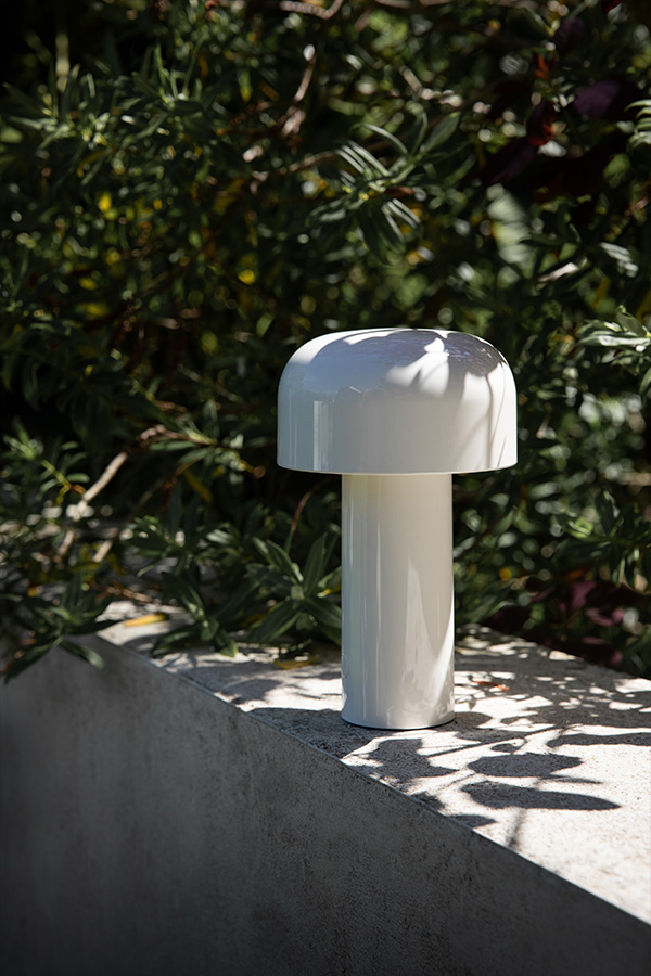 White Flos Bellhop Portable Table Lamp surrounded by plants