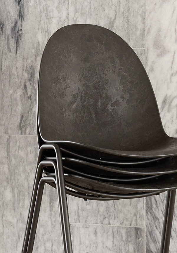 Three Mater Eternity Sidechairs stacked in front of a marble wall