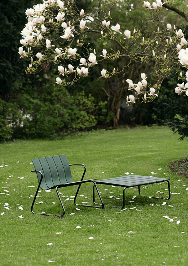 A green Mater OC2 lounge chair and table under a magnolia tree