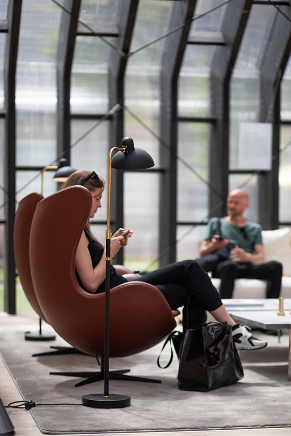 A woman sitting in the Anniversary Edition Egg Chair inside the Fritz Hansen Pavillion