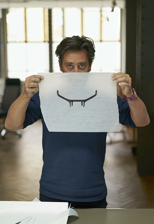 Designer Jay Osgerby holding up some trace with a sketch on it