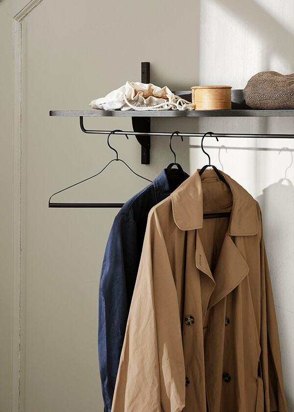 A Ferm Living Sector Rack Shelf with clothes hanging