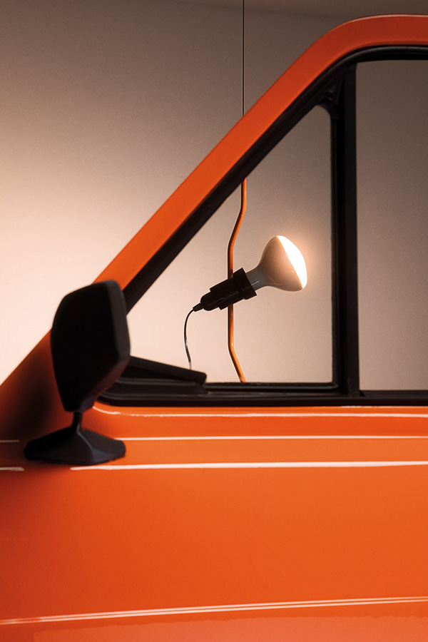 An orange parentesi lamp next to an orange car door