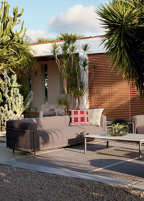 An outdoor living room featuring the LC10-P coffee table and the LC3 Sofa