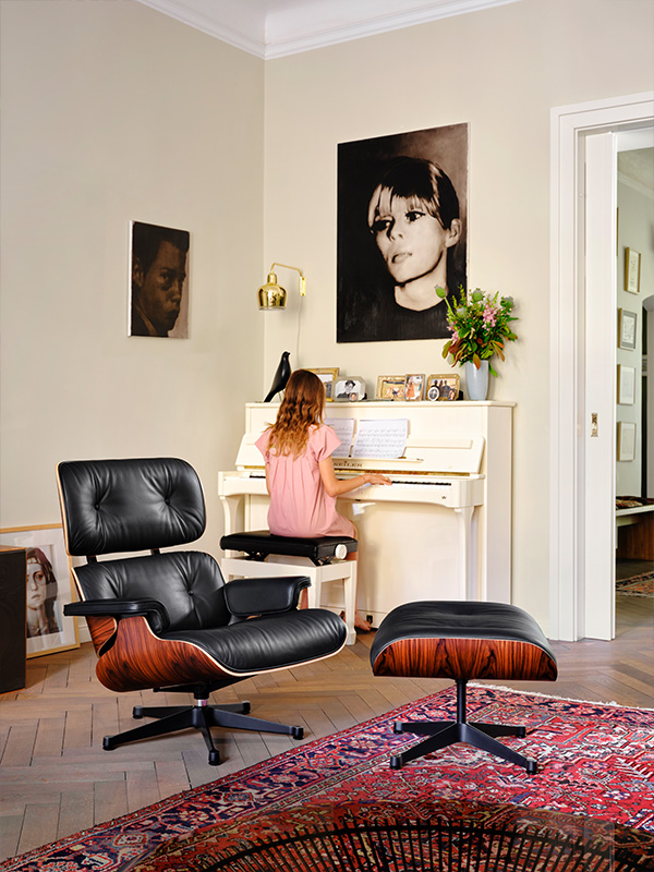 An Eames Lounge Chair in front of a girl playing piano