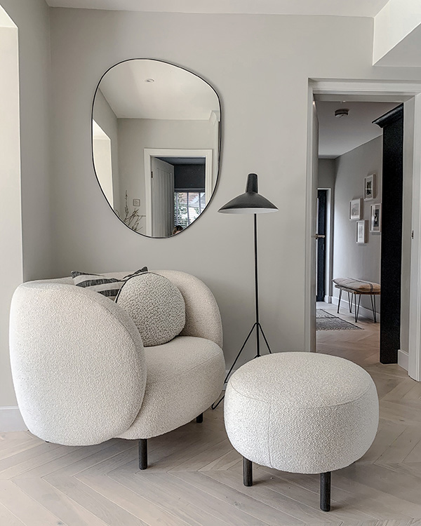 A curvy white lounge chair next to the &Tradition HM8 Tripod Floor Lamp