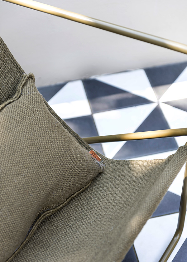 A detail shot of the Ferm Living Desert Lounge Chair against geometric tiles