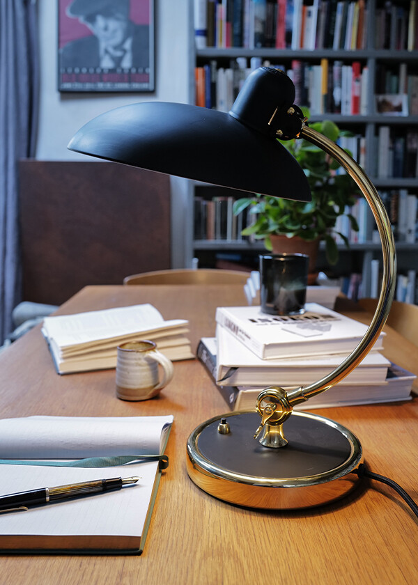 A close up of the Special Edition Brass Fritz Hansen Kaiser Idell 6631-T Luxus Table Lamp on Christen Pears' wooden desk in her home office.