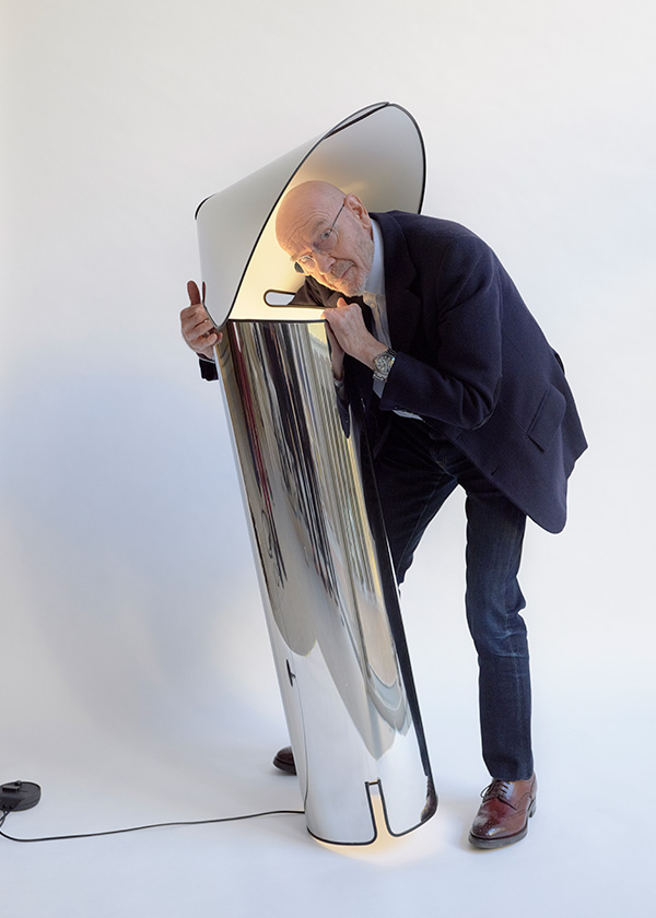 Mario Bellini looking down into the stem of a large Chiara floor lamp