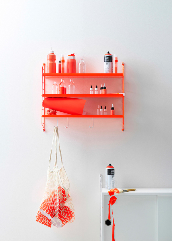 The String Pocket Metal in orange neon, holding bright coloured objects.