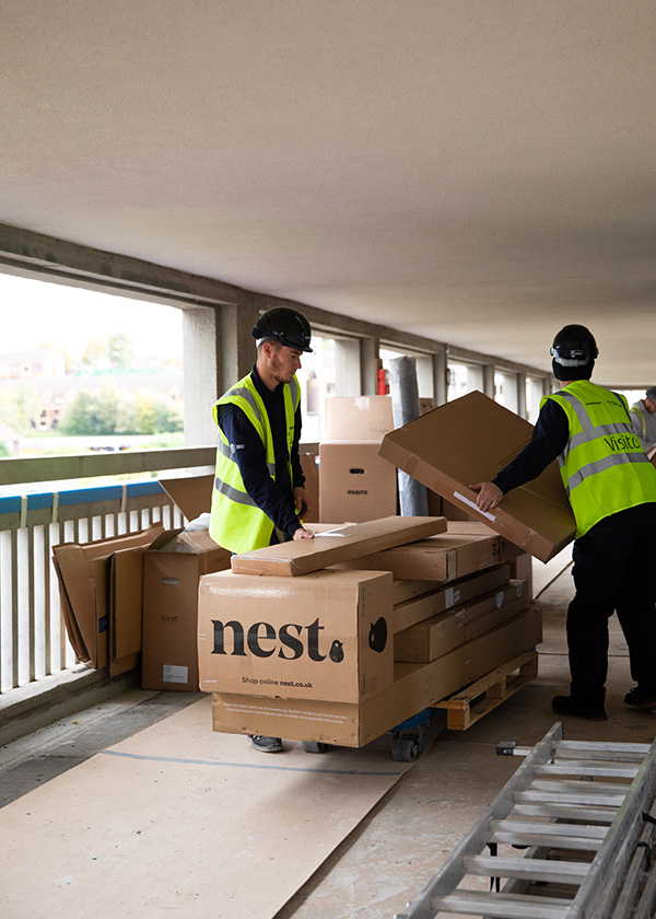 two men in high vis jackets carrying Nest boxes