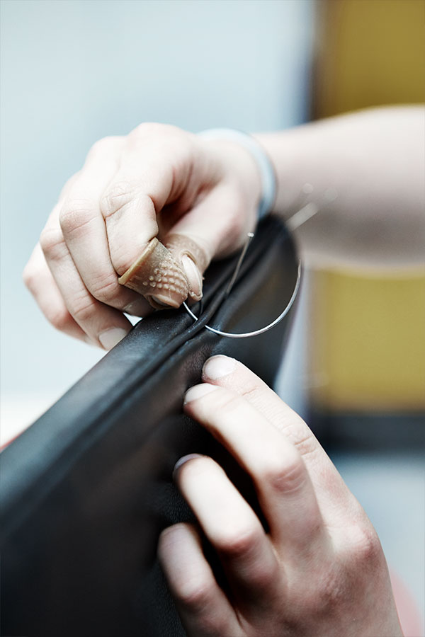 Someone stitching the leather upholstery on a Carl Hansen & Son chair