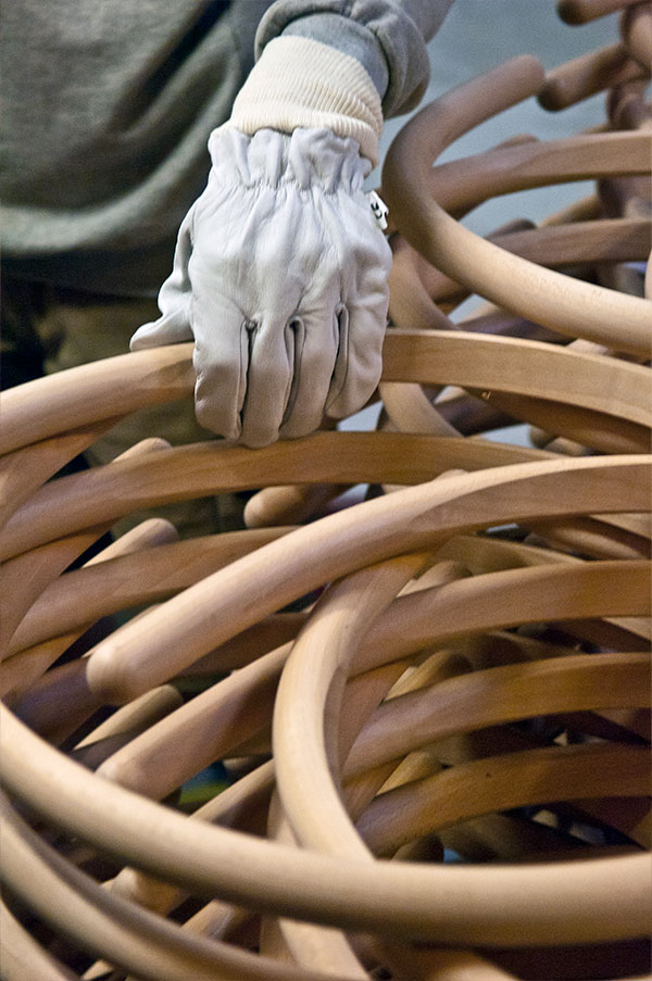 Someone lifting a part of the CH24 Wishbone Chair in the Carl Hansen & Son factory