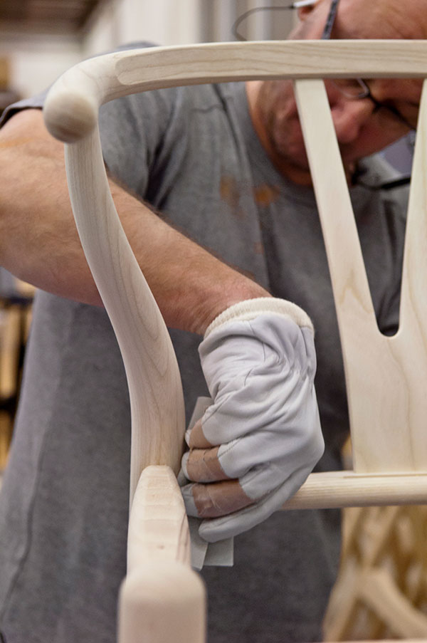 Someone sanding the frame of the Carl Hansen & Son Wishbone chair