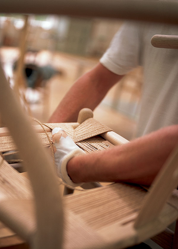 Someone weaving the seat on the Carl Hansen and Son CH24 Wishbone Chair