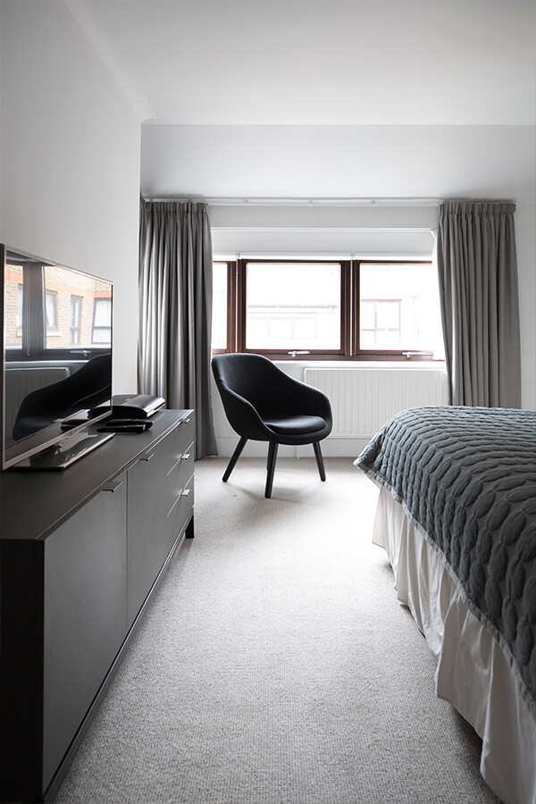 The Hay About A lounge Chair inside the bedroom at Monarch House Apartments