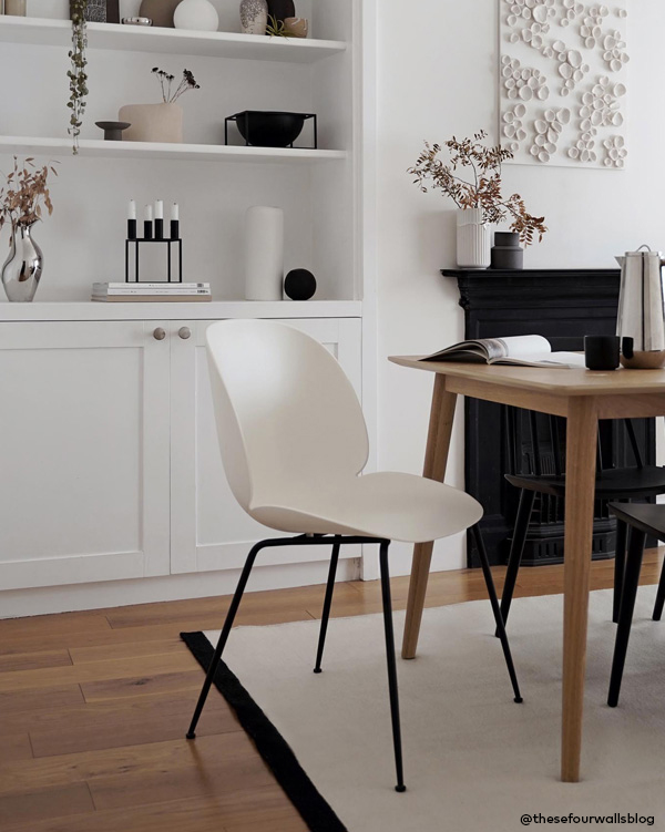 Pink and burgundy Gubi Beetle chairs with brass legs against a dark wall