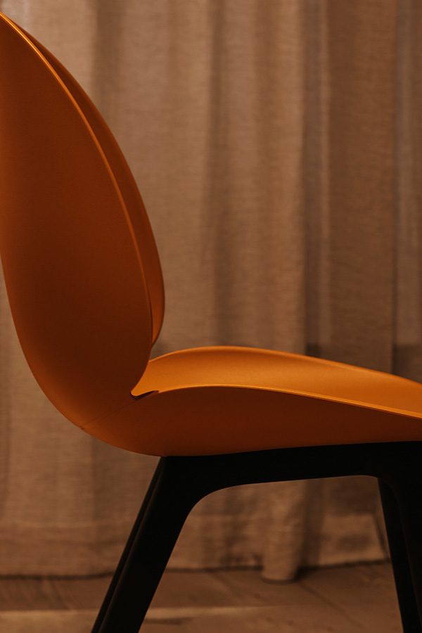 A close up of an upholstered Gubi Beetle Chair shell