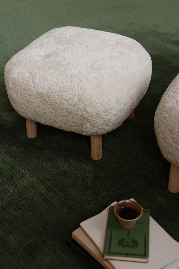 A close up of the ATD1 Little Petra Pouf on a green rug