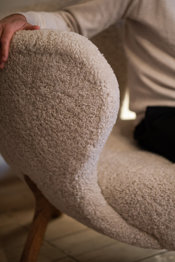 A person sitting on a sheepskin upholstered Little Petra lounge chair