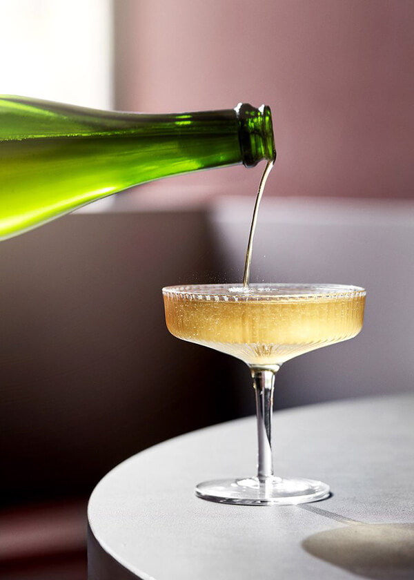 Sparkling wine being poured into the Ferm Living Ripple Champagne Saucer