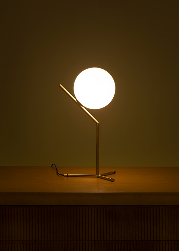 A brass Flos IC T1 table lamp on a wooden sideboard