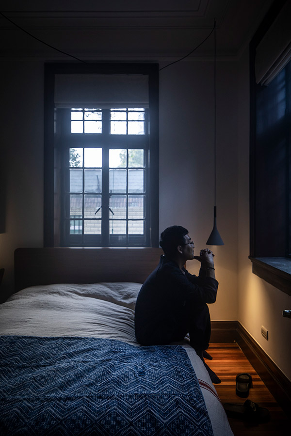 Man sitting on bed next to the Foscarini aplomb pendant