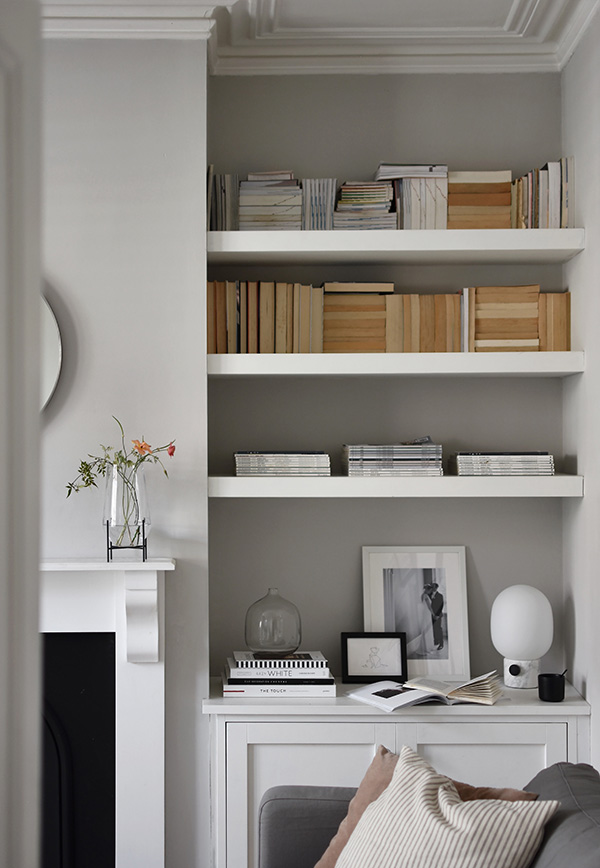 Corner of a living room with shelving and the Echasse Vase on a fireplace