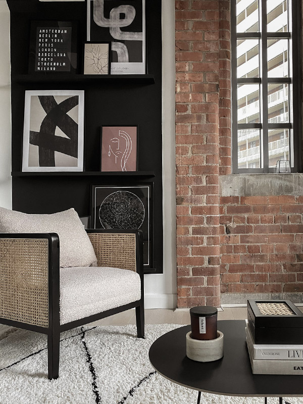 A rattan lounge chair next to an exposed brick wall