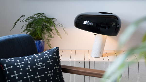 Flos Snoopy Table Lamp on a shelf behind an armchair