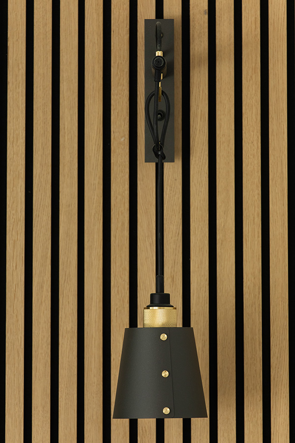 A Buster + Punch Hooked Wall Light against a wooden panelled wall