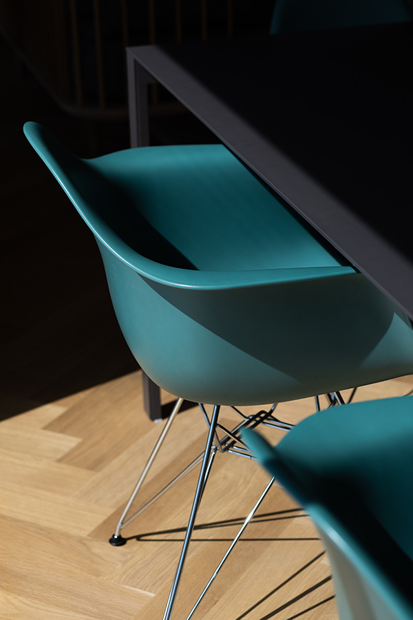 Looking down on two teal Vitra Eames Shell Chairs at a black dining table