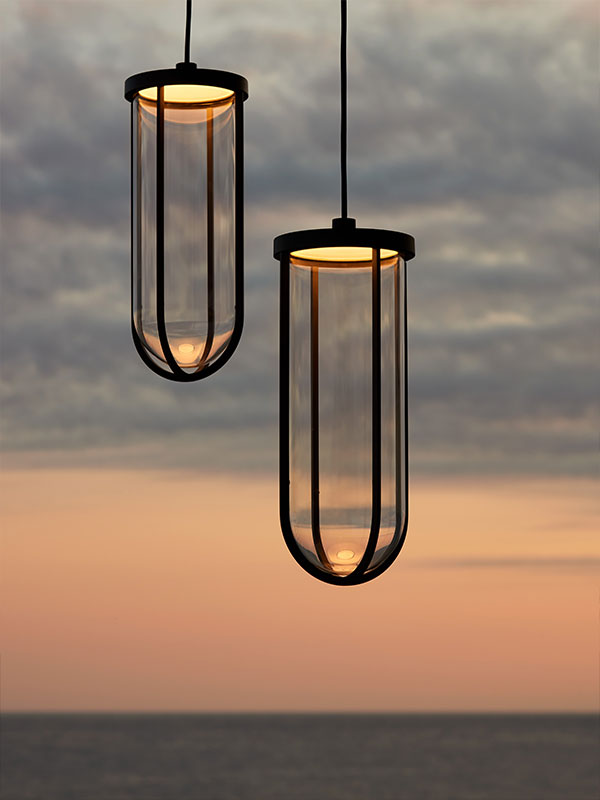 Two Flos In Vitro outdoor suspension lights hanging in front of a sunset