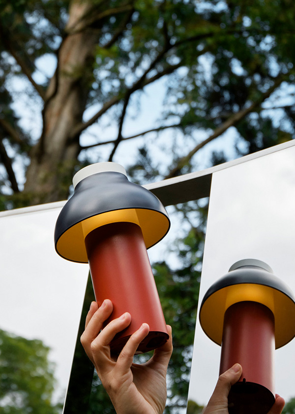 Red and black HAY PC Portable Table Lamp being held up to the sky