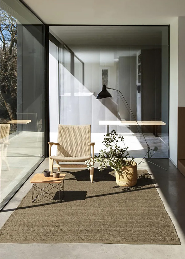 A warm neutral lounge nook featuring a CH25 Lounge Chair, Eames LTR Table and Nanimarquina rug