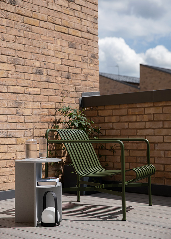 Green HAY Palissade Lounge Chair and Audo Copenhagen Carrie Lamp on a roof terrace