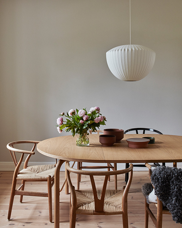 A warm minimal dining room featuring CH24 wishbone chairs and a Nelson Bubble Pendant