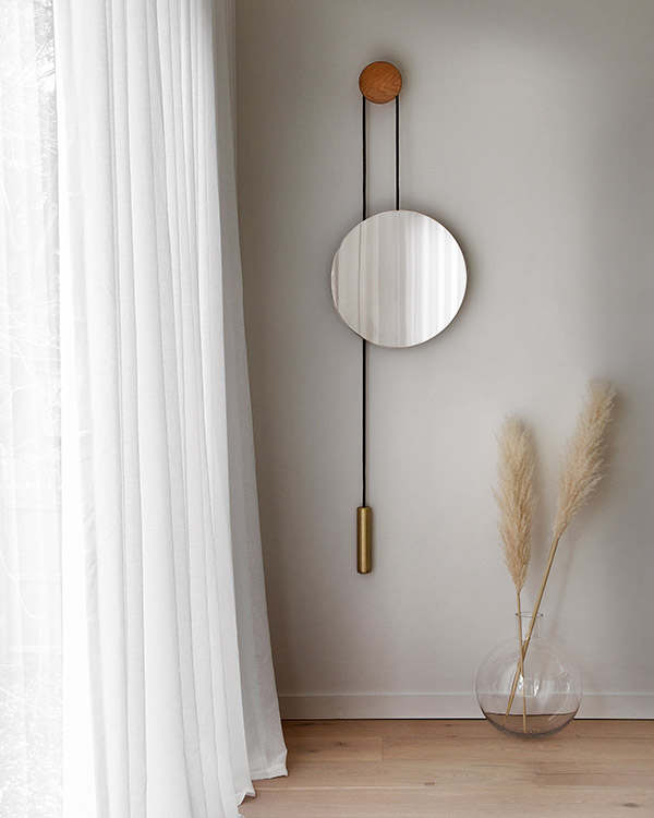 New Works Rise & Shine Mirror next to white drapes