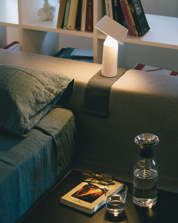 White Marset Bicoca portable table lamp on the arm of a sofa