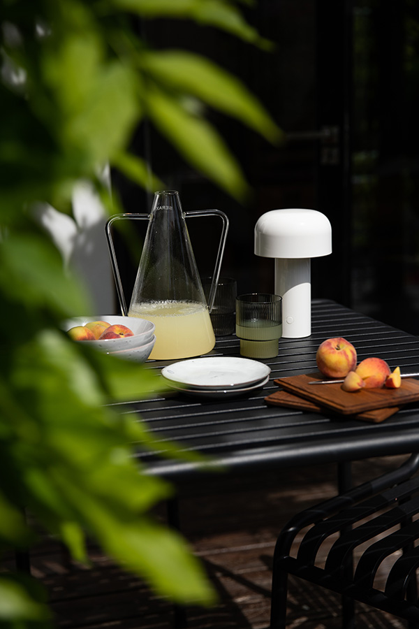 The Flos Bellhop and Serax Carafe on a HAY Palissade outdoor table