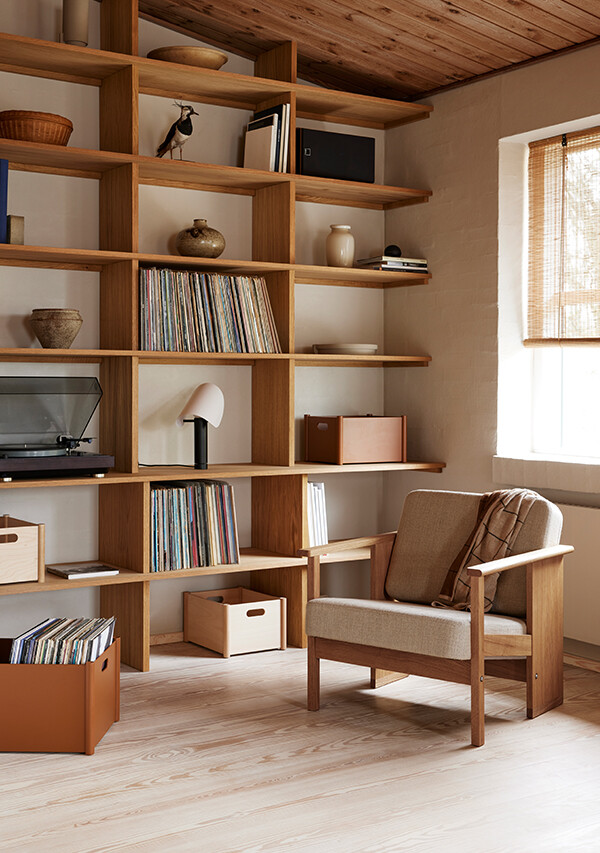 Form & Refine Block Lounge Chair, next to a large wooden shelf