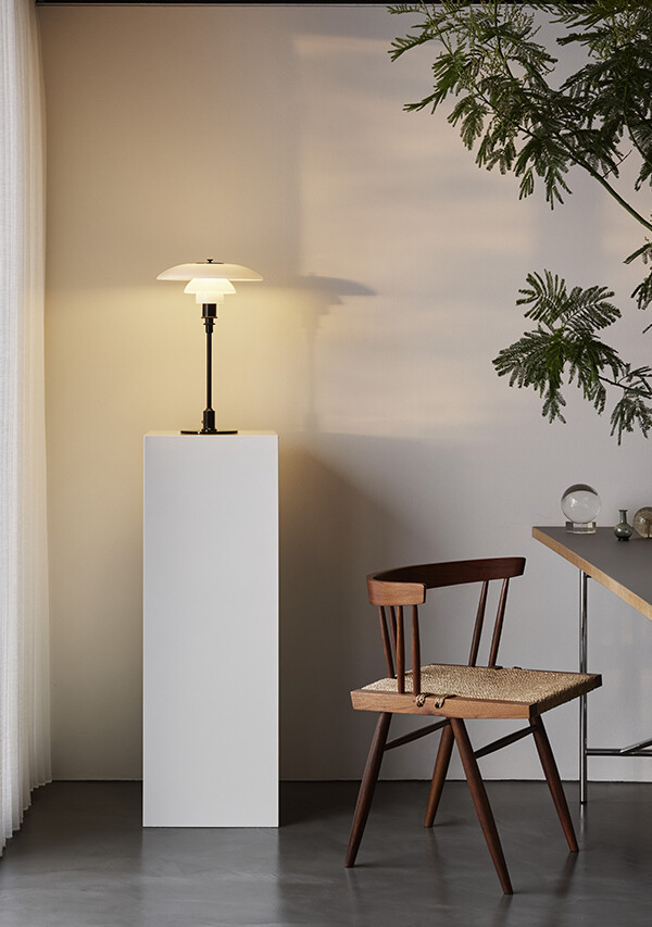 Louis Poulsen PH 3½-2½ Glass Table Lamp on top of a plinth next to a wooden chair