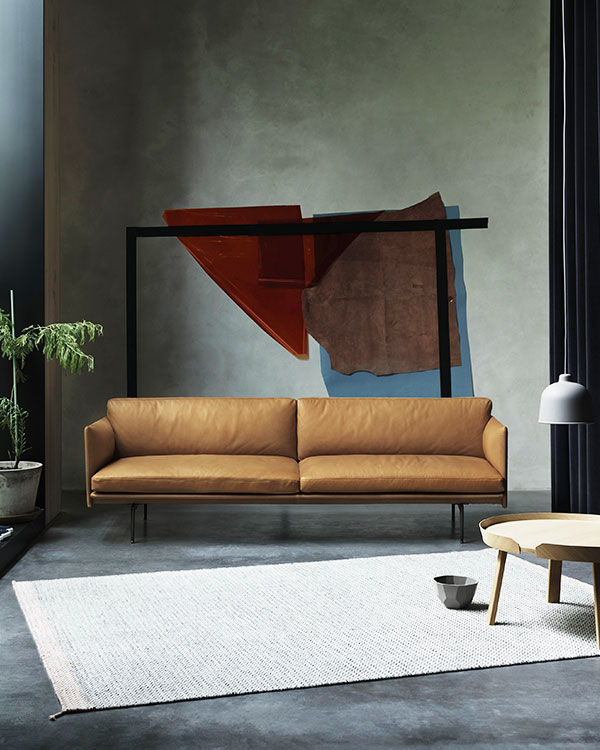 A brown leather Muuto Outline Sofa in front of a piece of modern art