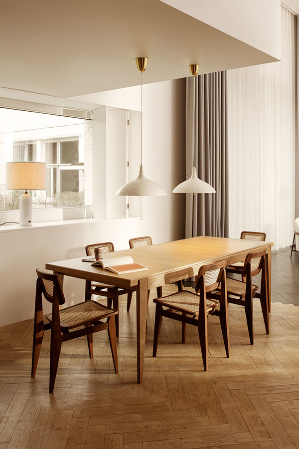 6 Gubi C-Chairs surrounding a large wooden dining table