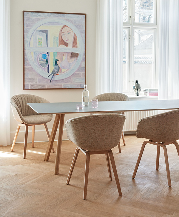 Four upholstered HAY About A Chair's around a modern dining table