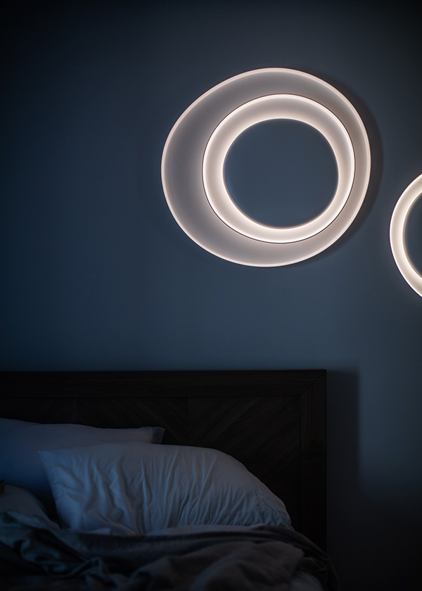 Foscarini Bahia wall light above a bed in a dark room