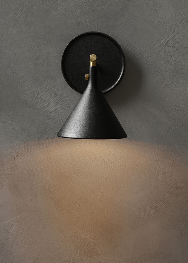 Audo Copenhagen Cast wall sconce giving out a glow